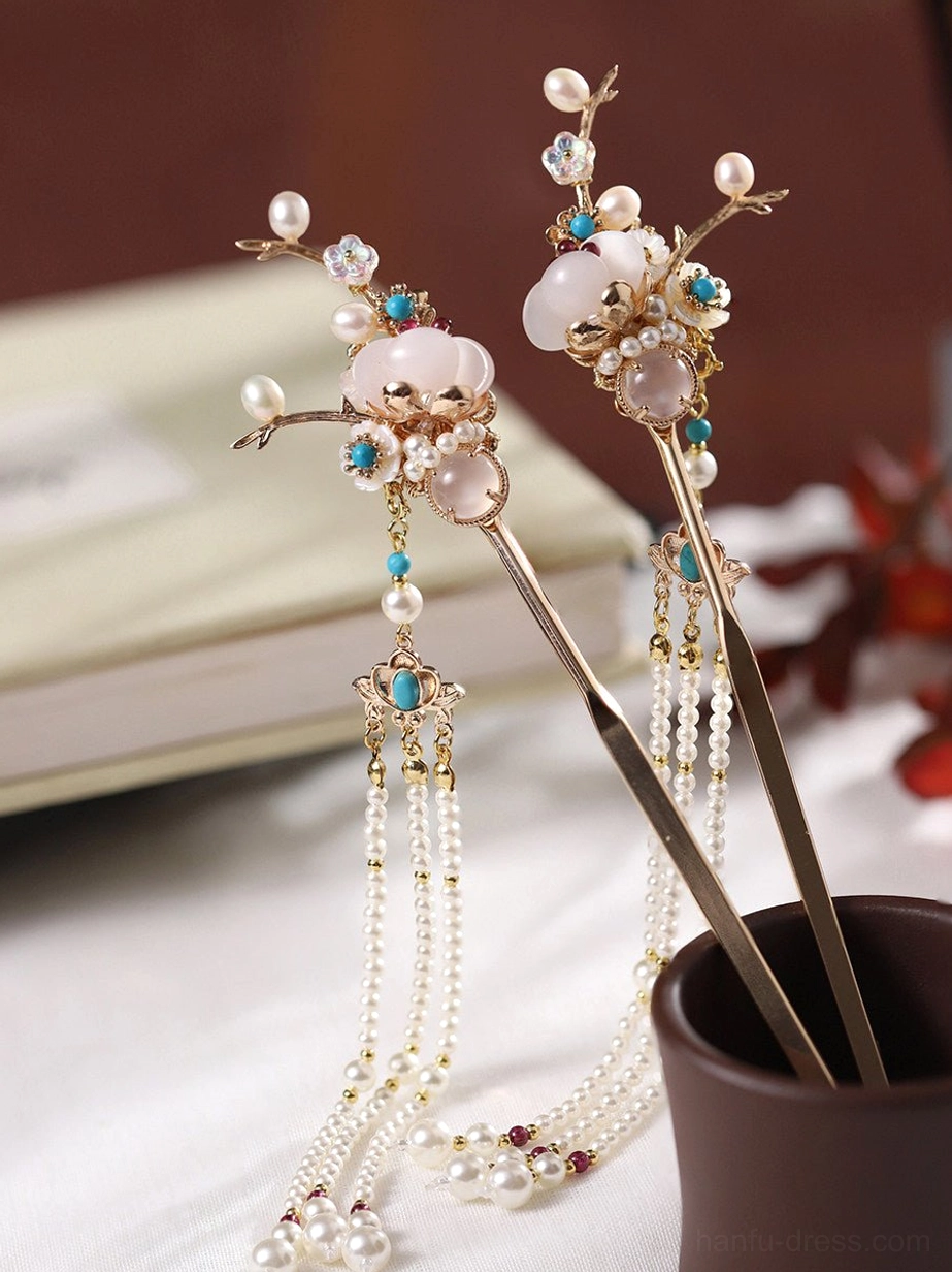 Oblique view of a pair of vintage Chinese hair sticks with gold branch details, milky white stones, blue accents, and long pearl tassel pendants