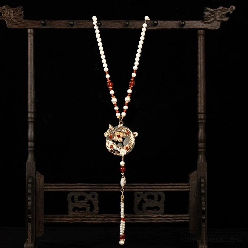Vintage Chinese long necklace with red and white beaded chain gold floral pendant and short decorative tassel on wooden jewelry stand