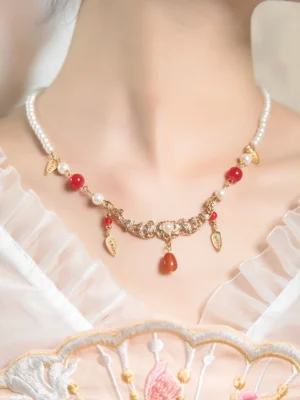 Vintage Chinese pearl choker necklace with red agate teardrop pendant and gold leaf charms worn with pink embroidered Hanfu
