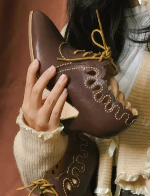 Close-up of rich brown vintage Chinese shoes showing tan contrast laces, scalloped vamp detailing, decorative stitching, and a curved block heel
