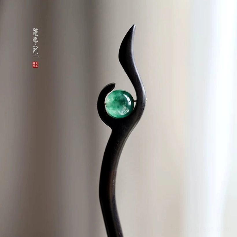Vintage Chinese wooden hair stick with smooth black body, patterned green jade ornament, and elegant curved swirl design
