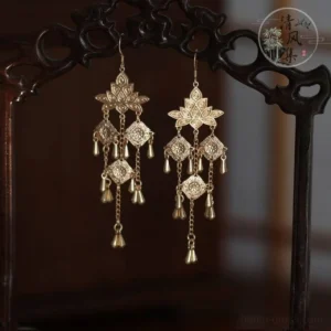 Vintage style gold Chinese tassel earrings with layered openwork floral ornaments on traditional carved wooden chair