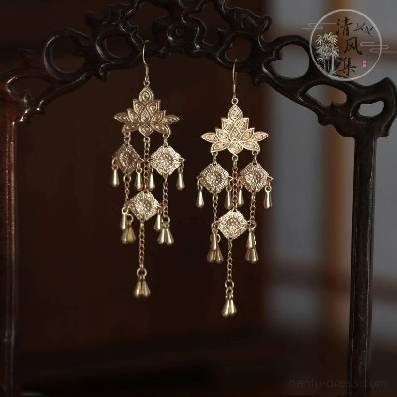 Vintage style gold Chinese tassel earrings with layered openwork floral ornaments on traditional carved wooden chair