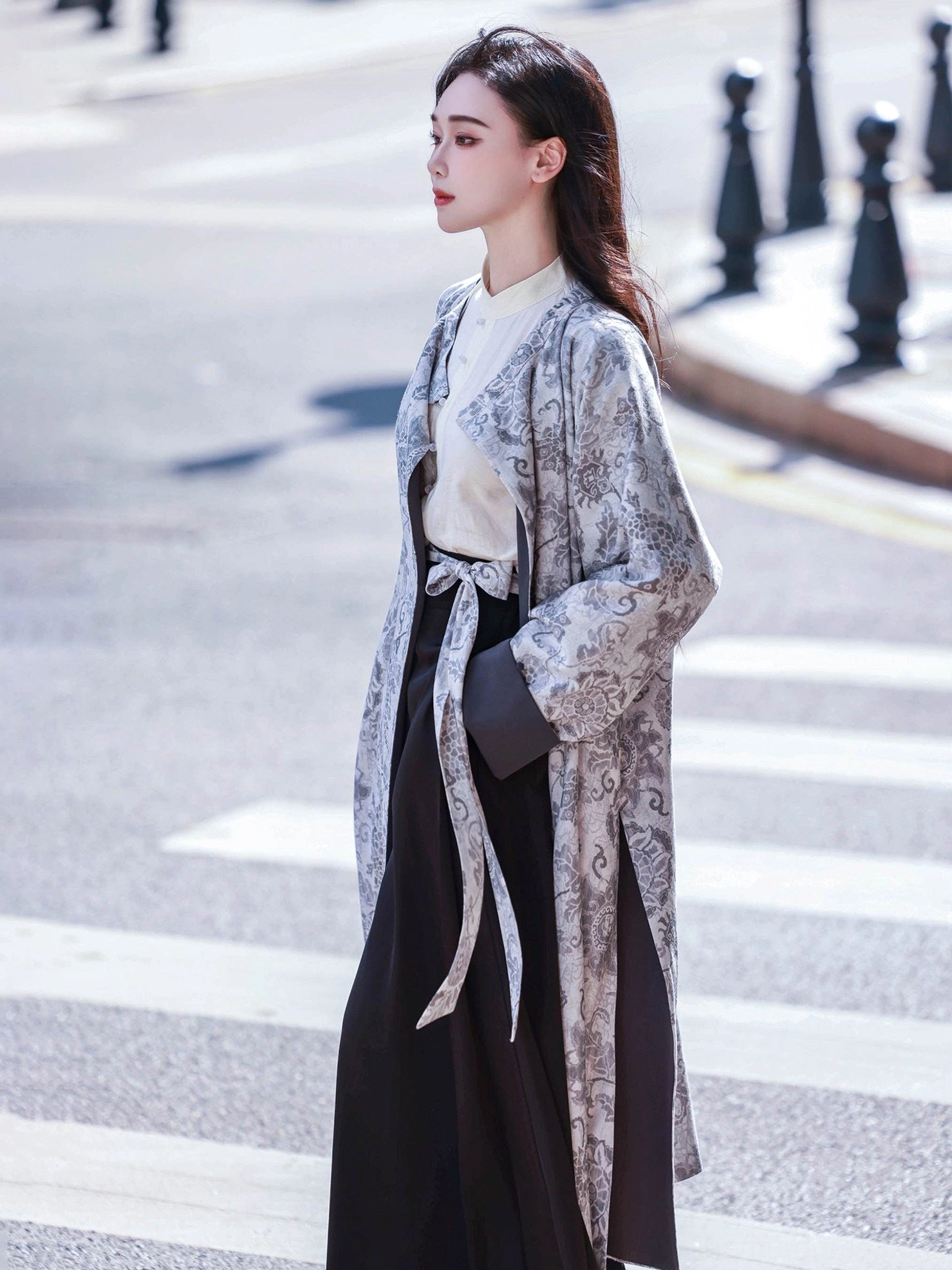 Side view of a woman wearing the vintage gray floral side of a reversible Tang Dynasty inspired Hanfu robe with loose sleeves tied waist sash and black long skirt