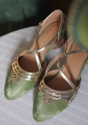 Pair of vintage green and metallic gold Chinese qipao shoes displayed in a flat lay, showing ornate cutout toe decorations, soft insoles, crisscross Mary Jane straps, and low block heels