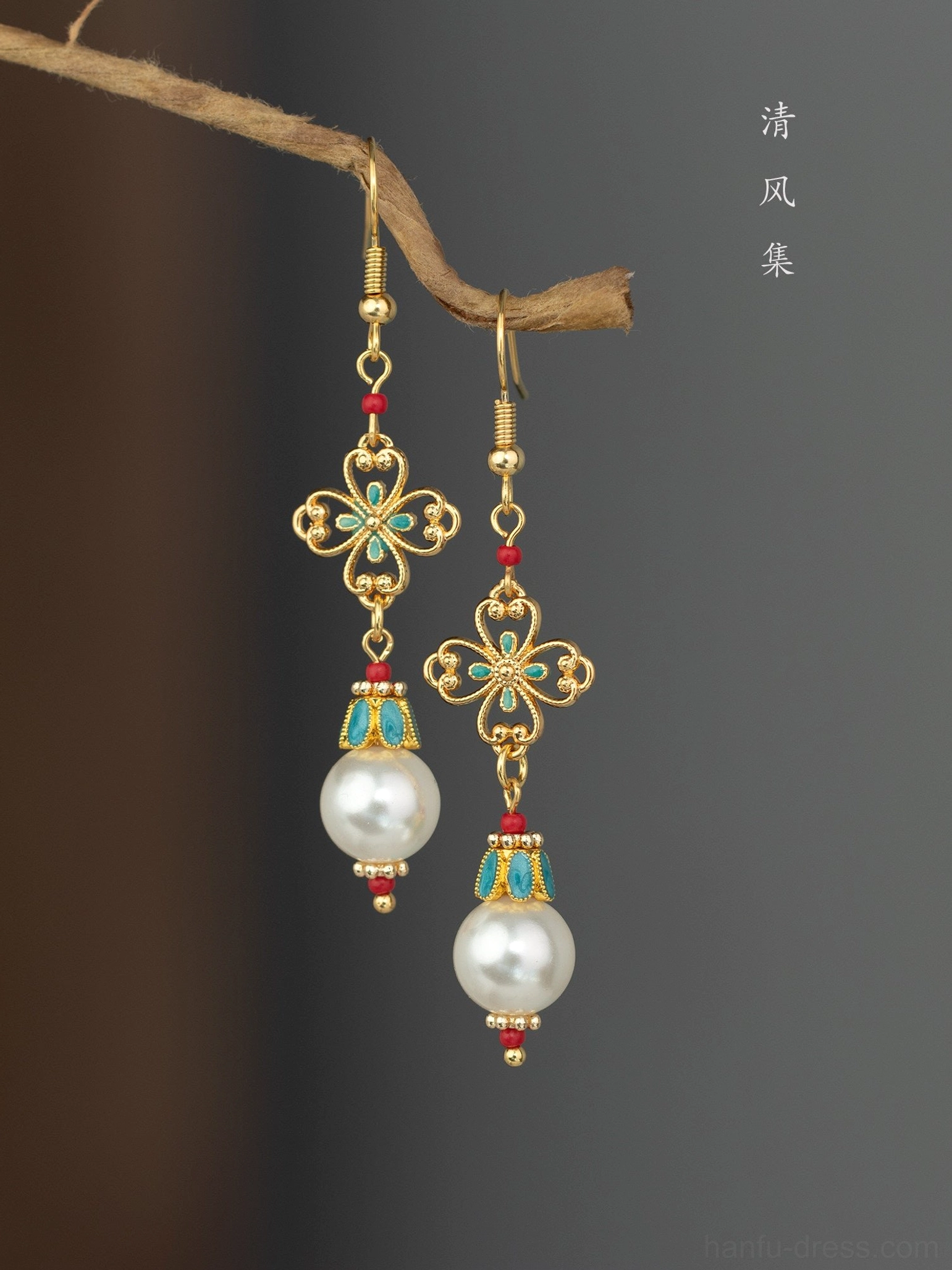 Vintage inspired Hanfu Chinese earrings with white pearl drops gold filigree charms turquoise enamel accents and red decorative beads angled close up