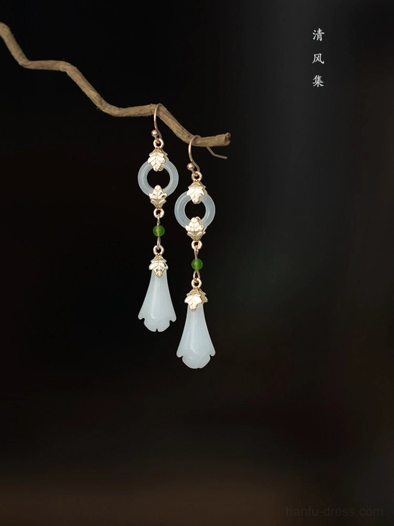 Vintage inspired magnolia Hanfu earrings with delicate gold filigree style accents white floral pendants and green bead details on dark brown background