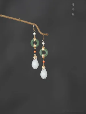 Vintage Chinese Hanfu drop earrings with jade green crystal rings white magnolia flower pendants pearl beads and gold tone hooks displayed on a twig