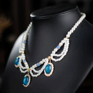 Front three-quarter view of a vintage multi-strand Chinese necklace displayed on a black jewelry mannequin, with white pearl chains, blue bead details, and three dark blue oval gemstone-style pendants