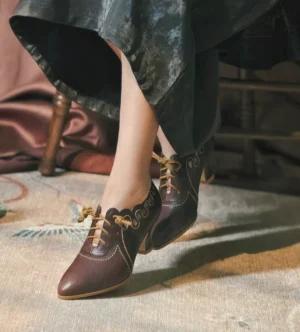 Model wearing dark brown vintage Qipao lace-up heels with pointed toes and scalloped detailing, styled with a dark satin skirt in a classic indoor setting