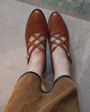 Top view of tan brown vintage Mary Jane heels with adjustable crisscross buckle straps, pointed toe Chinese shoes styled with a retro skirt