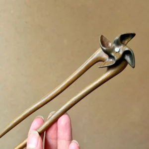 Waiting for Wind wooden Chinese hair stick held in hand, featuring a double-pronged Hanfu hairpin design with natural wood grain, windmill-shaped top, and small silver floral accent