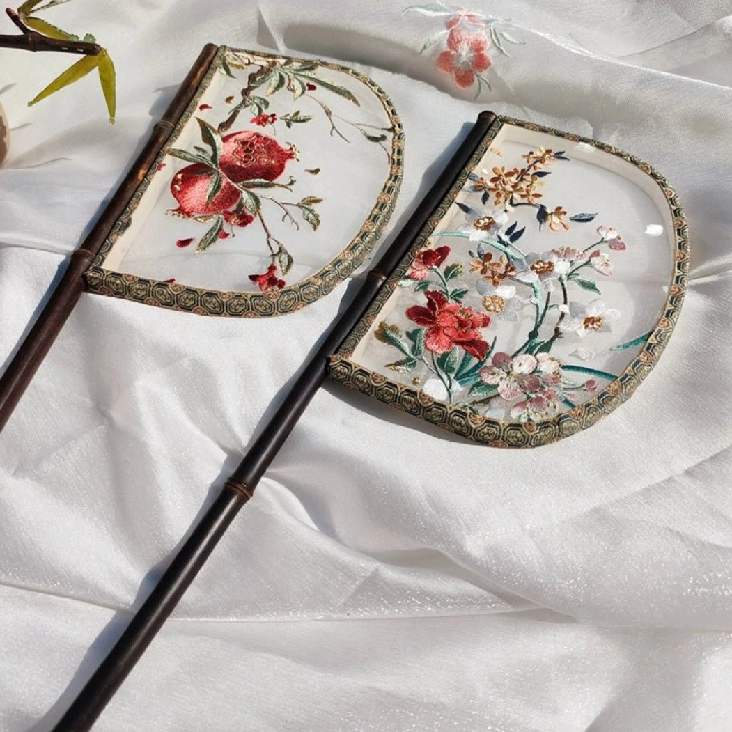 Flowers style half-moon embroidered Chinese hand fan with dark bamboo handle and decorative stitched edge on white satin