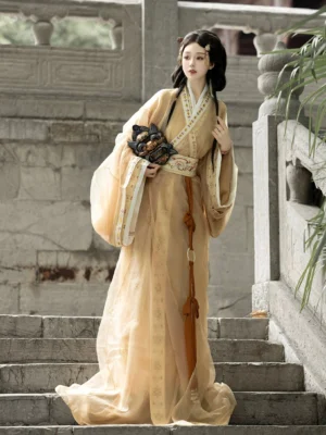 Yellow beige Warring States Han Dynasty straight hem Hanfu robe set with sheer wide sleeves and embroidered belt in a traditional stone courtyard