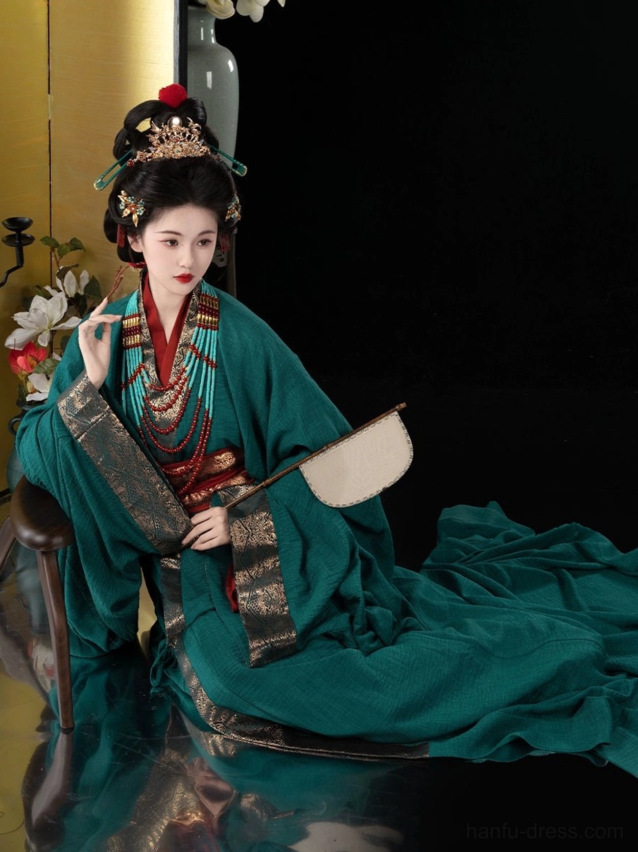 Seated Warring States inspired Hanfu costume in emerald green with red inner layer, gold trim, long robe train, and traditional silk fan