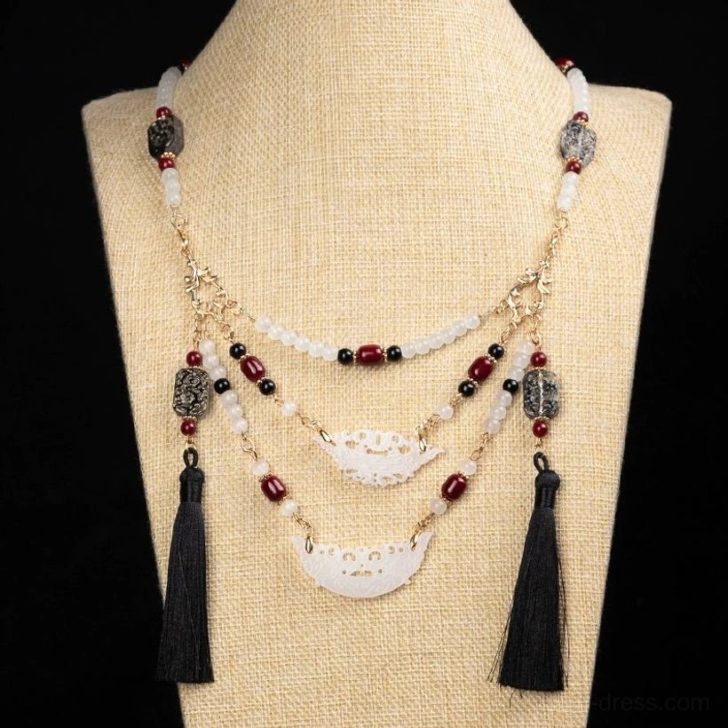 Front view of Warring States inspired multilayer Chinese necklace on linen dress form with balanced black tassels and red black white gold color palette