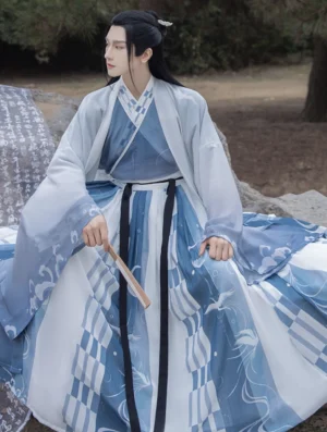 Male model seated outdoors wearing blue gradient Wei Jin style hanfu for men with cross collar layers, wide sleeve outer coat, and printed qiyao ruqun skirt