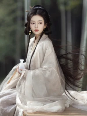 Front three-quarter seated view of an ethereal Wei Jin Dynasty Hanfu robe with loose wide sleeves and floor-length drape, styled with a white porcelain wine vessel