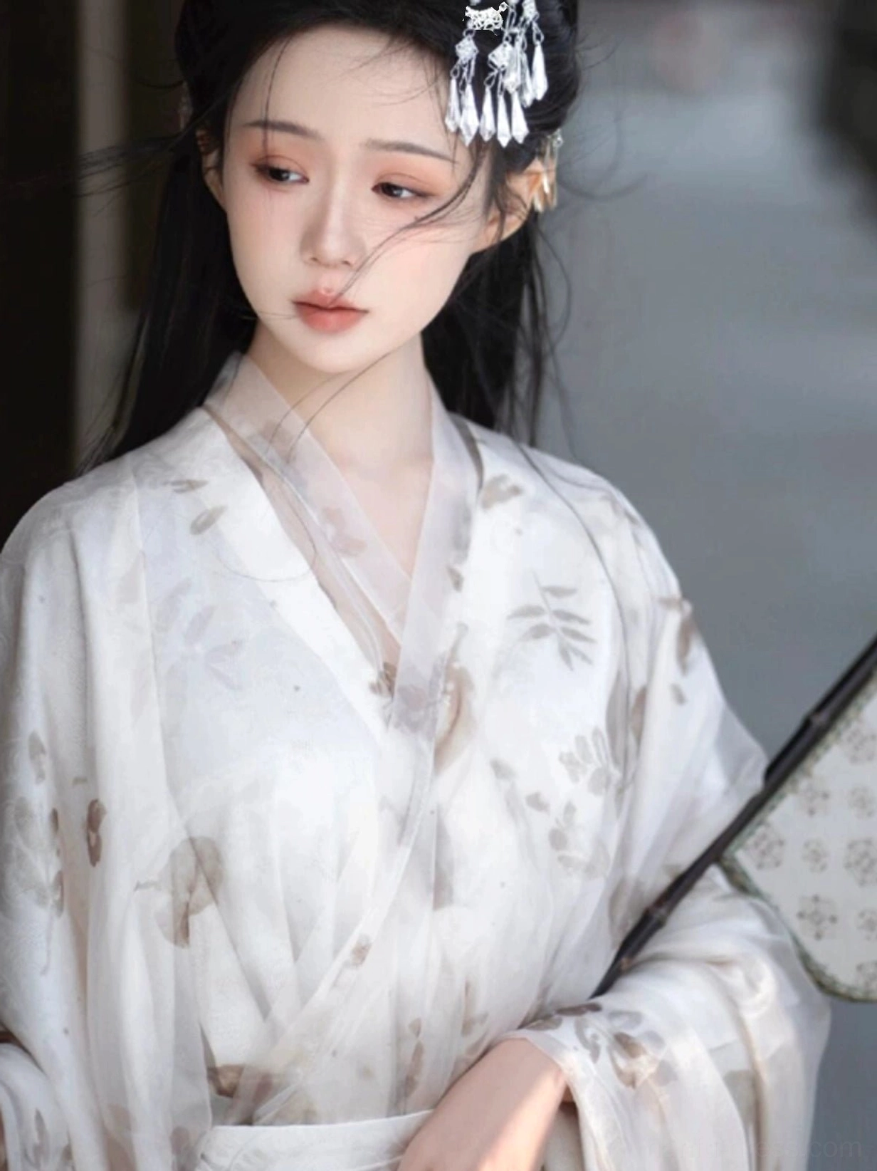 Close-up of the translucent cross-collar upper robe from a Wei Jin Dynasty Hanfu with delicate leaf and flower prints, wide sleeves, low neckline and traditional silk fan