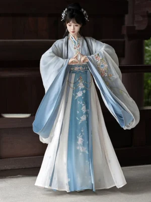 Blue and white gradient Wei Jin Dynasty Qiyao Ruqun Hanfu full front view with floral details, wide sleeves, cross-collar top, and flowing wrap skirt in a traditional Chinese courtyard