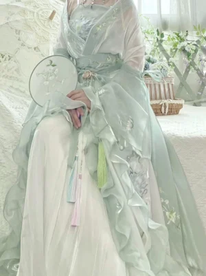 Close-up of mint green Qiyao Ruqun Hanfu waist embroidery tassel ornaments and flowing chiffon skirt with round silk fan