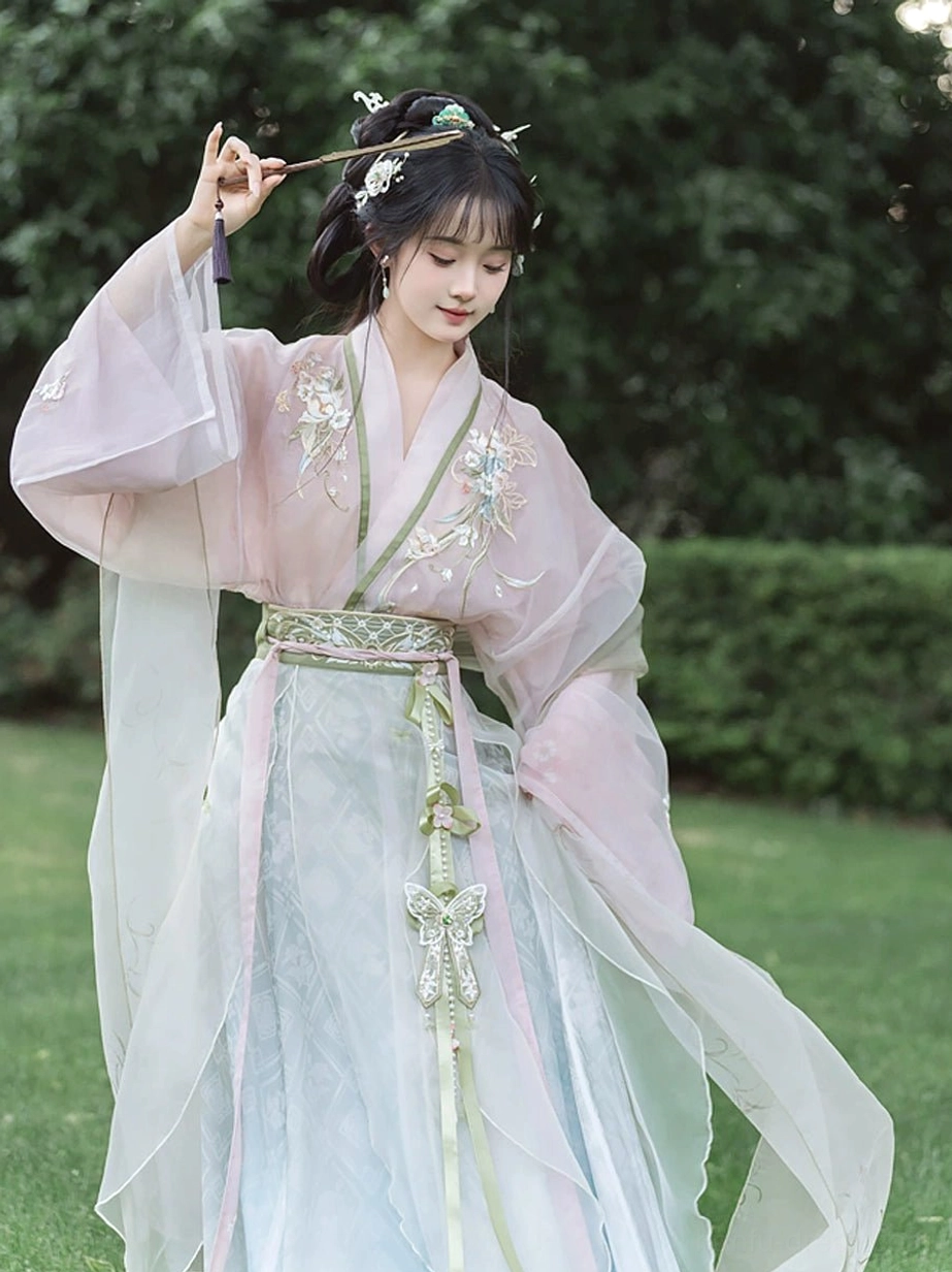 Close-up of Wei Jin Dynasty Qiyao Ruqun Hanfu floral embroidery, pink upper garment, green waist trim, butterfly hanging ornament, and elegant flowing silhouette