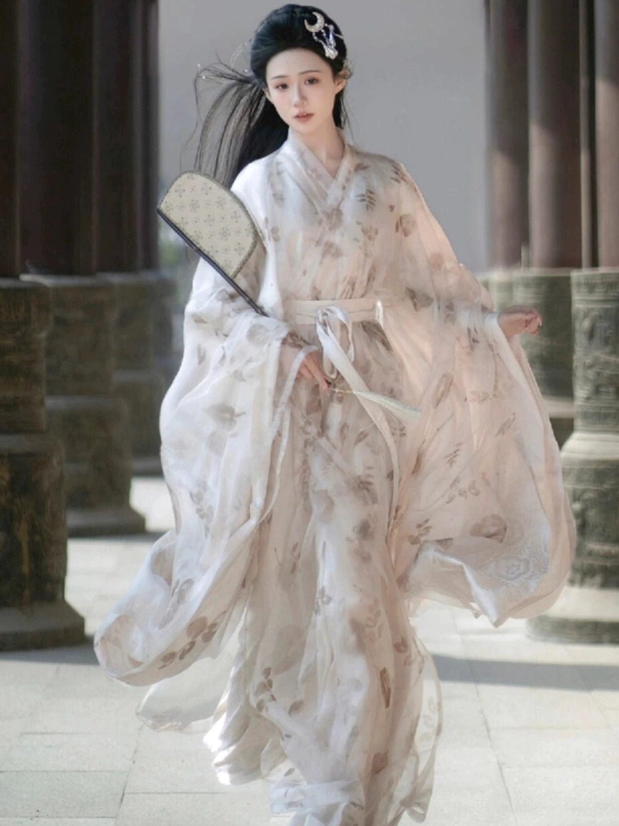 Full-body front view of a woman wearing an off-white Wei Jin Dynasty Qiyao Ruqun Hanfu with wide sheer sleeves, dried-flower prints, cross collar and white sash in a classical Chinese courtyard