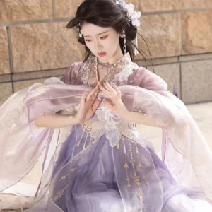 Close up front view of a woman in a purple Wei Jin Dynasty Qiyao Ruqun Hanfu with sheer wide sleeves, lace trimmed neckline, golden tassel waist decoration, and floral hair ornaments