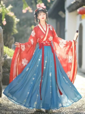 Wei Jin Dynasty Qiyao Ruqun Hanfu full body front view with red floral cross collar robe, blue pleated skirt, red waist sash, and wide flowing sleeves in a traditional Chinese garden