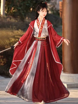 Wei Jin Dynasty Qiyao Ruqun Hanfu warrior costume in red and ivory with golden cloud embroidery, wide sleeves, flowing skirt, and traditional Chinese sword in a wooden pavilion