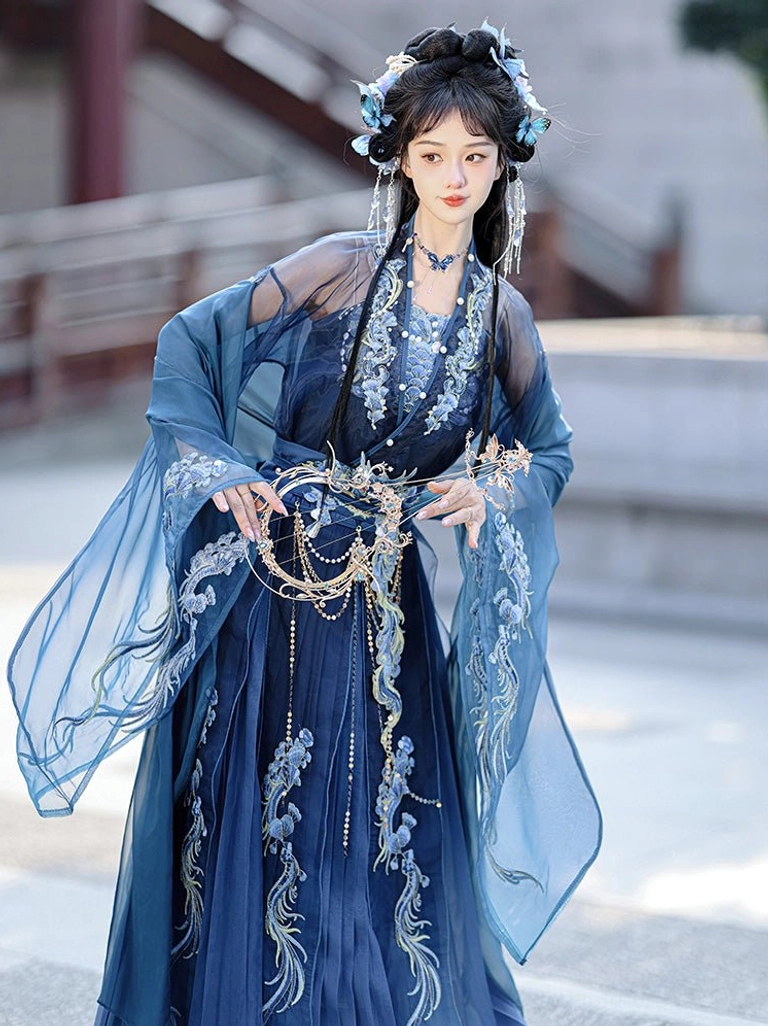 Wei Jin Dynasty-inspired blue Hanfu close-up featuring gold-thread dragon and cloud embroidery, beaded waist chain, sheer outer sleeves, and layered bodice