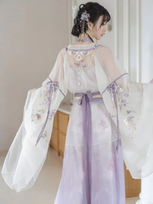 Back view of a lavender Wei Jin Dynasty Hanfu dress showing flowing sheer-style wide sleeves, floral skirt print, purple waist sash, and decorative pearl pendant