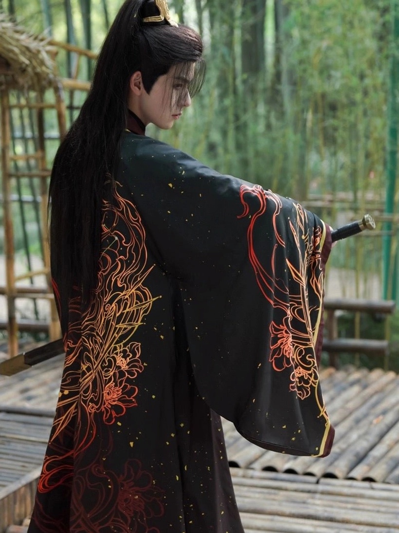 Rear three-quarter view of a male Wei-Jin Wuxia Hanfu coat in black with large flame and floral back decoration, extra-long wide sleeves, and traditional long hairstyle in a bamboo forest