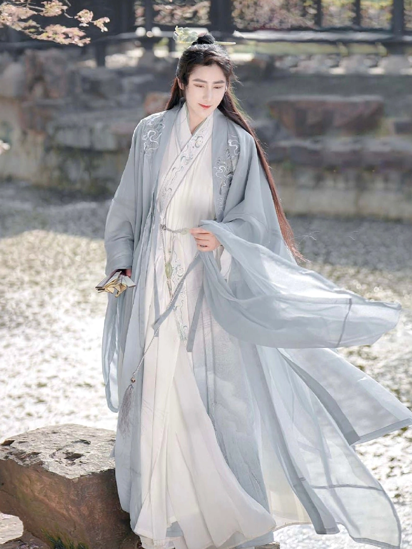Wei Jin xianxia male hanfu shown in a Chinese waterside garden with a pale blue outer robe and flowing white inner layer