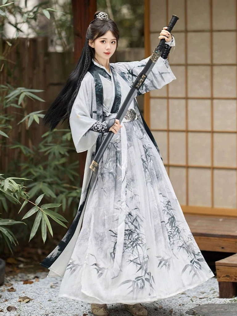 White Wei Jin Dynasty Hanfu with bamboo ink painting skirt, dark-trimmed cross collar, ornate waist belt, and flowing layered silhouette photographed beside bamboo and wooden doors
