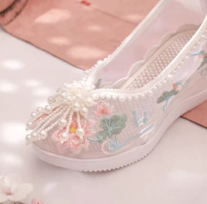 Close-up of a white Chinese Hanfu shoe with breathable mesh upper pearl collar trim lotus embroidery pearl toe tassel and thick non-slip wedge platform sole