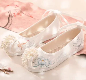 White embroidered Hanfu shoes with crane cloud and blue lotus motifs, pearl tassels, and ankle ribbon ties