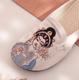 Close-up of a white traditional Chinese Hanfu shoe featuring colorful Peking Opera beauty embroidery, blue and pink floral details, Chinese knot accent, and breathable linen insole