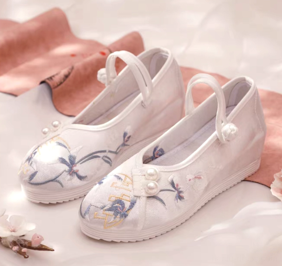 Pair of white embroidered Chinese Hanfu shoes for women with blue floral and crane embroidery, golden traditional motifs, pearl decorations, Chinese knot ankle straps, and low wedge rubber soles