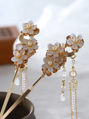 Left oblique close-up of white floral tassel Chinese hair stick with gold-tone frame, pearl-like flower centers and opal-look beaded pendants for Hanfu