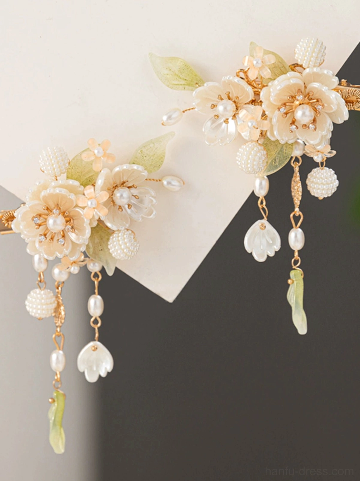 Pair of white flower Hanfu hair clips with faux pearl centers, pale green leaves, gold-tone frames, and dangling pearl tassels