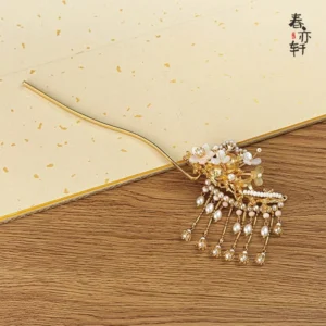 Overhead view of gold toned Chinese Hanfu hairpin with white flower beads and layered pearl tassels