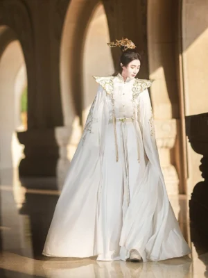 White and gold Xianxia Hanfu costume for men and gender neutral wear shown in full length front three quarter view with flowing imperial cloak