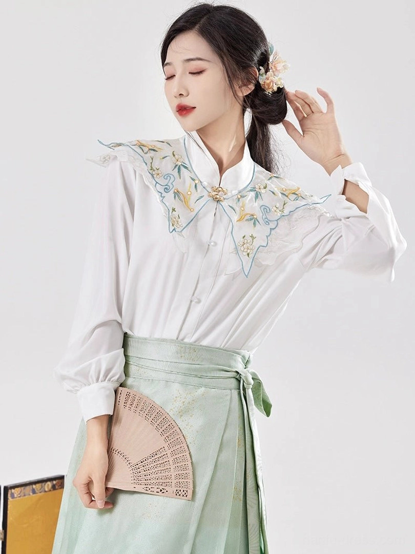 White stand collar Hanfu blouse with blue and gold floral embroidered cloud collar paired with light green mamianqun skirt