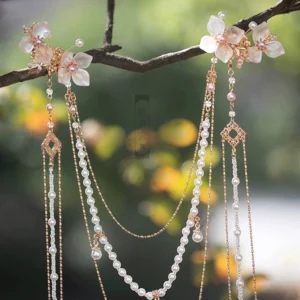 White hibiscus Chinese hair pin accessories displayed on a tree branch, with translucent flower ornaments, pearl bead chains, diamond pendants and long tassels