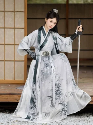 White ink-wash Wei Jin Dynasty Hanfu outfit with bamboo print skirt, dark-trimmed cross-collar top, decorative metal waist belt, and matching embroidered arm accessories worn by a female swordswoman