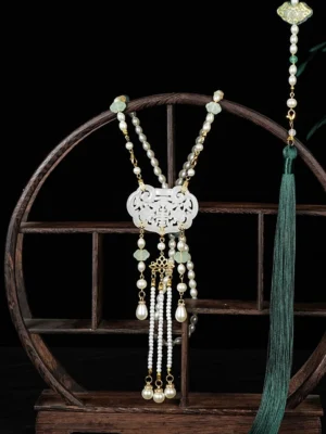Front view of a traditional Chinese long life lock tassel necklace with hollow white jade-style pendant, gold chains, pearl-like beads, light green jade accents, and dark green Hanfu tassel