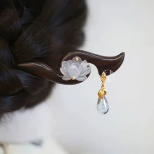 White lotus Chinese hair stick worn in braided updo with dark wooden pin, gold accents, and glass teardrop pendant