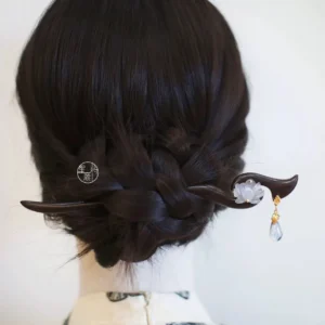 White lotus Hanfu hair accessory secured beside a traditional braided bun on mannequin against white background
