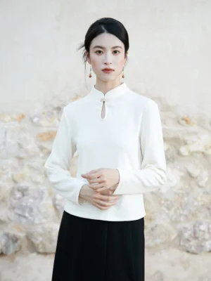 Front view of white modern Hanfu knitted top with Chinese stand collar, teardrop cutout and decorative frog button paired with black midi skirt